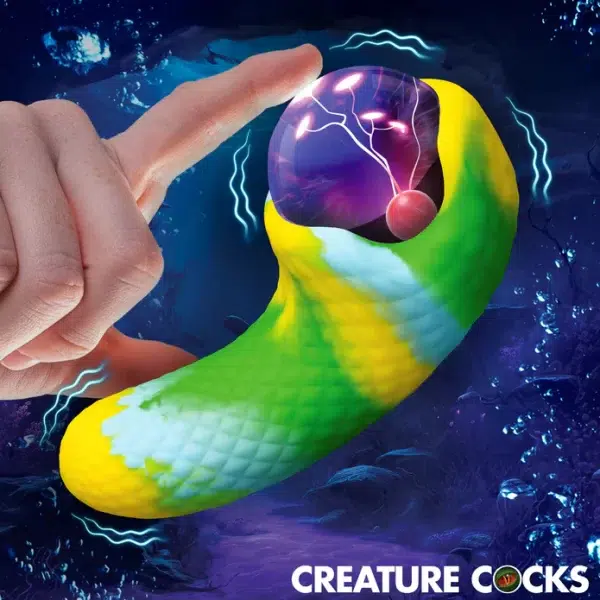 « Creature Cocks Electric Eye Plasma Vibrator posé sur un fond sombre mettant en valeur ses écailles vert‑bleu‑jaune ».